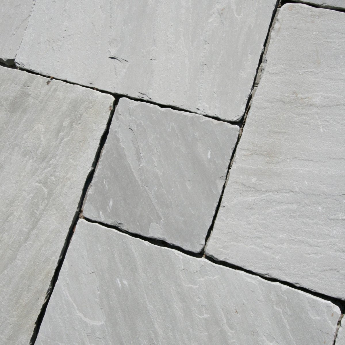 Graue Sandsteinfliesen von GREY, natürliche Sandstein- und Natursteinfliesen, geordnet auf einer Oberfläche.