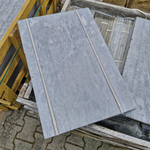 Helle getrommelte Marmorfliesen von CAMELIA, Naturstein, quadratisch, Oberfläche mit natürlicher Maserung, liegend auf einem Boden.