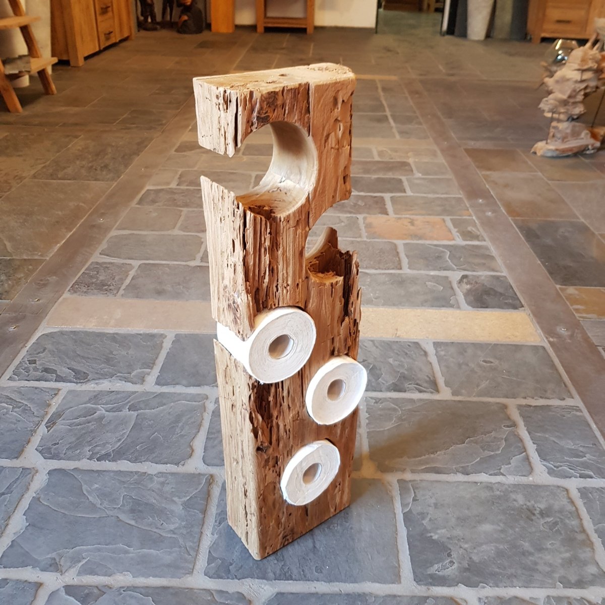 Ein einzigartiger Toilettenpapierhalter aus Teak-Altholz für Badgestaltung, sichtbar an einer modernen Toilette.